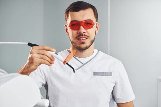 Portrait of professional dentist with equipment that standing indoors.