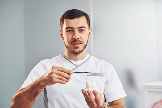 Portrait of professional dentist with equipment that standing indoors.