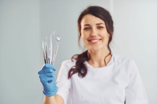 Portrait of professional female dentist with equipment that standing indoors.