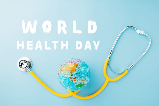 World Health Day. Yellow doctor stethoscope and world globe isolated on pastel blue background with copy space for text, Save world day, Green Earth Environment, Healthcare and medical concept