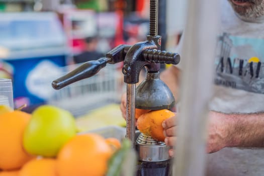 Freshly squeezed juice, street food. Man's hands making orange juice.