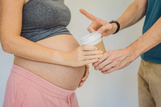 Husband forbids pregnant wife to drink coffee. A pregnant woman holds a cup of coffee in her hands. Caffeine safety, myths about coffee during pregnancy concept.