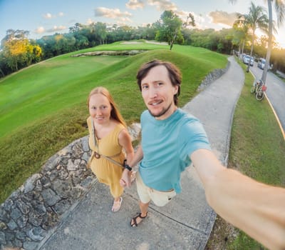 Husband with his pregnant wife walking on the golf course.
