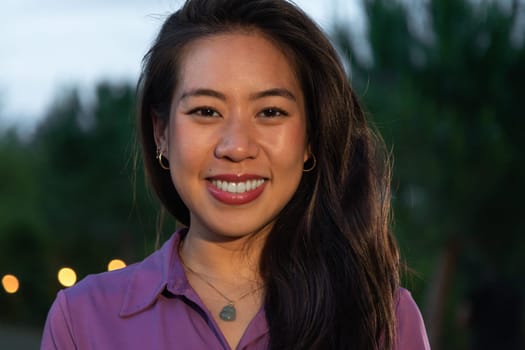 Headshot of young smiling asian woman at sunset. Lifestyle.