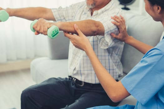 Contented senior patient doing physical therapy with the help of his caregiver. Senior physical therapy, physiotherapy treatment, nursing home for the elderly