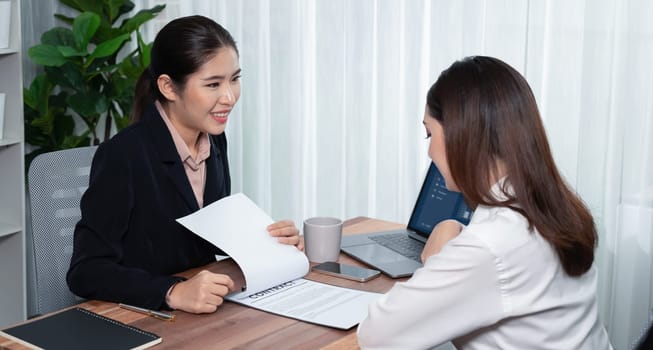 Business deal meeting, young businesswomen carefully reviewing terms and condition of contract agreement papers in office. Corporate lawyer give consultation on contract deal. Enthusiastic