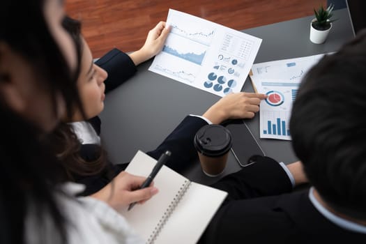 Harmony in office concept as business people analyzing dashboard paper together in workplace. Office worker sitting on meeting table with manager for discussion or strategy planning from top view.