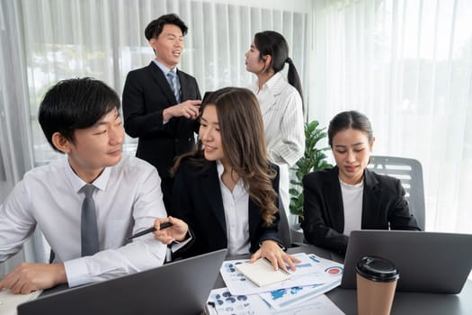 Harmony in office concept as business people analyzing dashboard paper together in workplace. Young colleagues give ideas at manager desk for discussion or strategy planning about project.