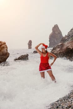 Woman travel sea. Young Happy woman in a long red dress posing on a beach near the sea on background of volcanic rocks, like in Iceland, sharing travel adventure journey
