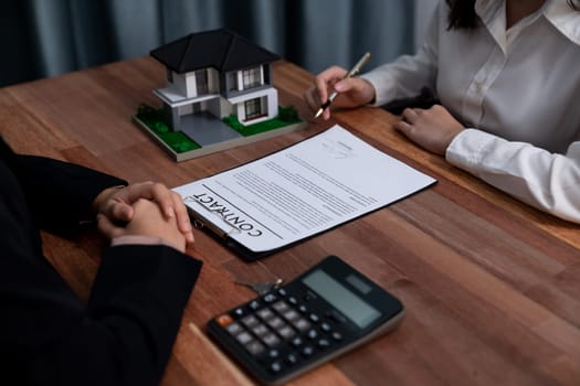 Completing the final step of the house loan process, the buyer signs the loan contract paper with a pen on the desk, securing the ownership of the property. Enthusiastic