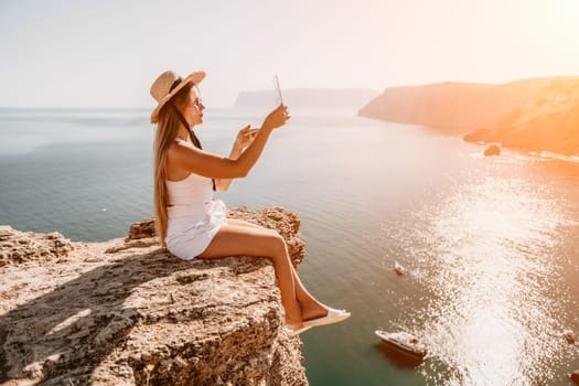 Digital nomad, Business woman working on laptop by the sea. Pretty lady typing on computer by the sea at sunset, makes a business transaction online from a distance. Freelance, remote work on vacation