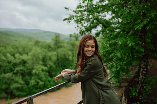 happy woman in a raincoat walks in the spring in the park near a stormy, mountain river. High quality photo