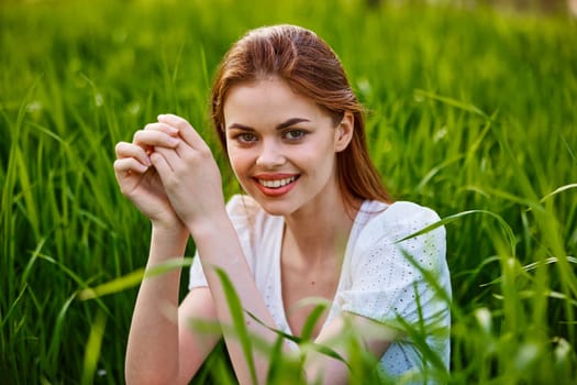 portrait of a woman sitting in the grass with her hands folded to her head. High quality photo