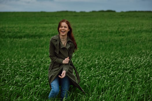 red-haired, happy woman stands in a green field in rainy weather. Emotions, harmony with nature. High quality photo
