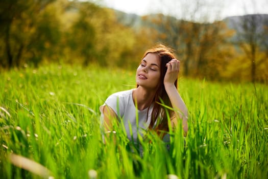 portrait of a pensive redhead woman sitting in the grass at sunset. High quality photo