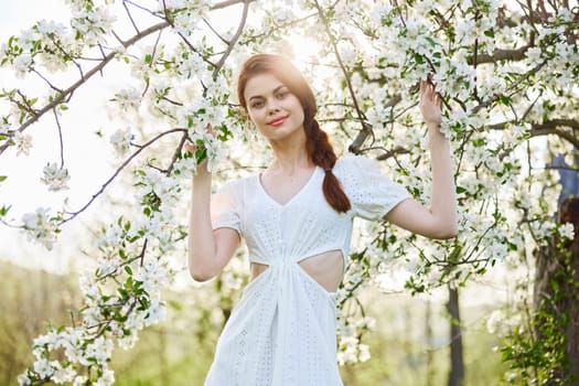 portrait of a happy, laughing red-haired woman next to a flowering tree in the garden. High quality photo