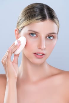 Alluring beautiful female model applying powder puff for facial makeup concept. Portrait of flawless perfect cosmetic skin woman put powder foundation on her face in isolated background.