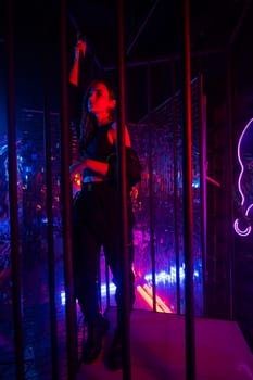 Caucasian woman in neon studio behind steel bars