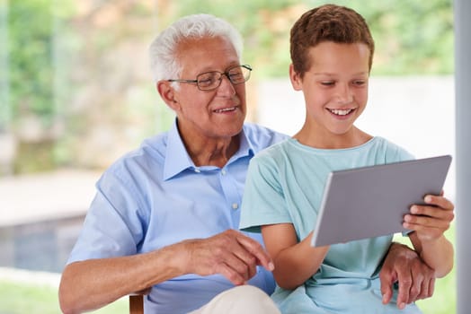 Learning about technology together. A boy using a digital tablet with his grandfather