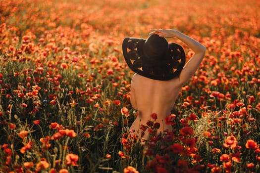 naked girl from behind in a black hat in a poppy field at sunset.