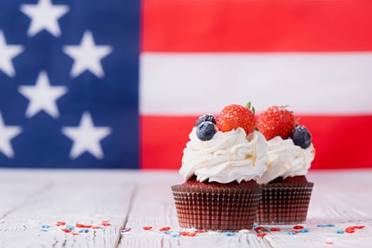 Fourth of july celebration.Sweet cupcakes with blueberries and strawberry , flag background