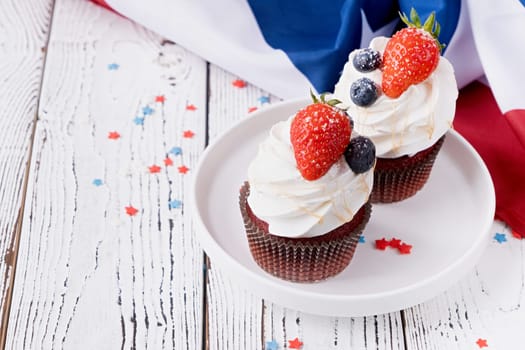 Fourth of july celebration.Sweet cupcakes with blueberries and strawberry , flag background