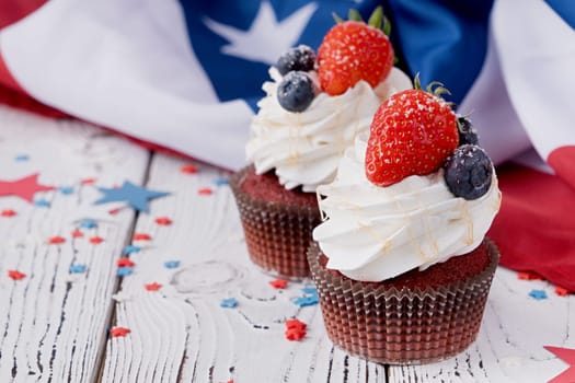 Fourth of july celebration.Sweet cupcakes with blueberries and strawberry , flag background