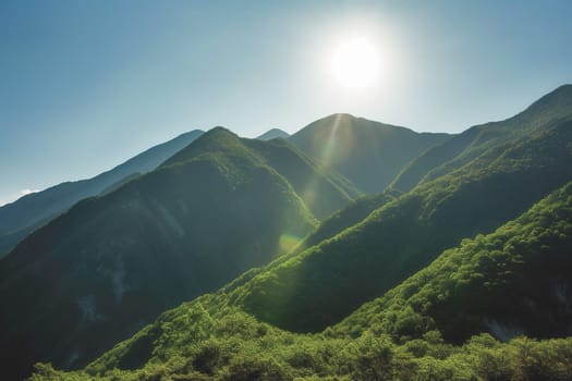 Beautiful sunrise over the green mountains in morning light with fluffy clouds on a bright blue sky. Nature freshness concept.