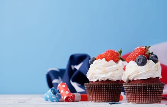 Fourth of july celebration.Sweet cupcakes with blueberries and strawberry , flag background