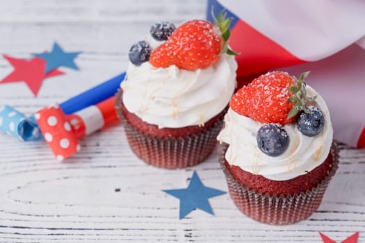 Fourth of july celebration.Sweet cupcakes with blueberries and strawberry , white wooden background