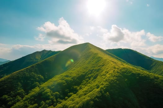 Beautiful sunrise over the green mountains in morning light with fluffy clouds on a bright blue sky. Nature freshness concept.