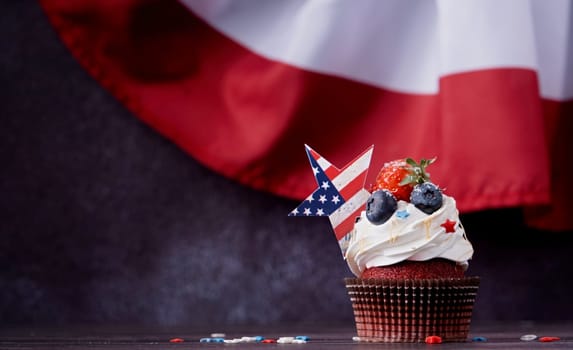 Fourth of july celebration. Sweet cupcakes with blueberries and strawberry over USA flag background