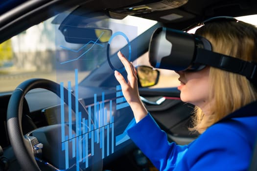 Digitally generated graphics and charts interface managed by business woman in vr googles sitting in the car in a blue suit. Metaverse cyber world technology concept.