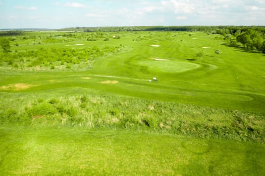 View from a distance of the golf course from a height. Green field and sand bunkers for playing golf.