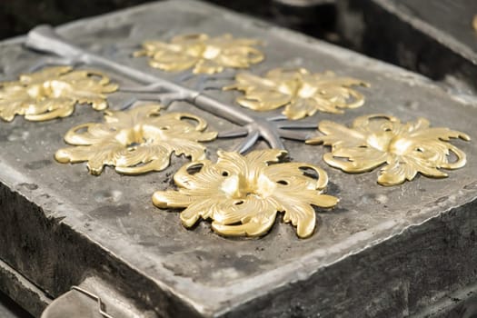 Stylish golden flower and grey branches molded in high precision cast in traditional production plant workshop extreme close view