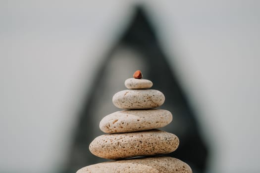 Pyramid stones on the seashore with warm sunset on the sea background. Happy holidays. Pebble beach, calm sea, travel destination. Concept of happy vacation on the sea, meditation, spa, calmness.