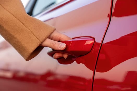 Woman opens the cars door by the hand, close up. Car sharing concept