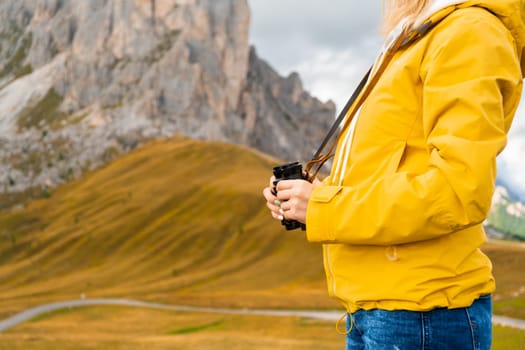 Woman explorer with binoculars in the mountain standing on the hill