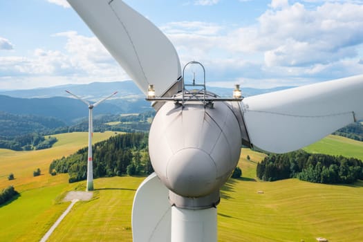 Close up a propeller of the windmill in the yellow field with mountains in the background