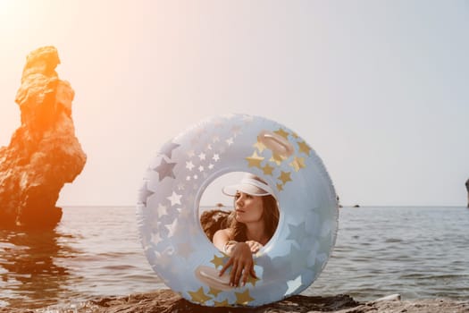 Woman summer sea. Happy woman swimming with inflatable donut on the beach in summer sunny day, surrounded by volcanic mountains. Summer vacation concept