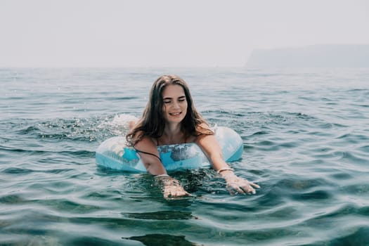 Woman summer sea. Happy woman swimming with inflatable donut on the beach in summer sunny day, surrounded by volcanic mountains. Summer vacation concept