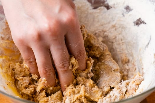 Close up of woman baker hands kneading the dough in the mixing bowl. Homemade pastry for cakes or cookies.