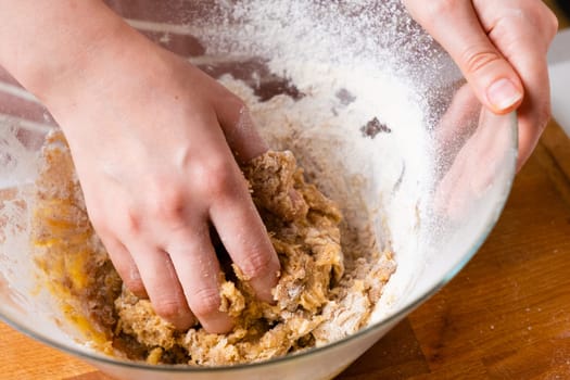 Close up of woman baker hands kneading the dough in the mixing bowl. Homemade pastry for cakes or cookies.