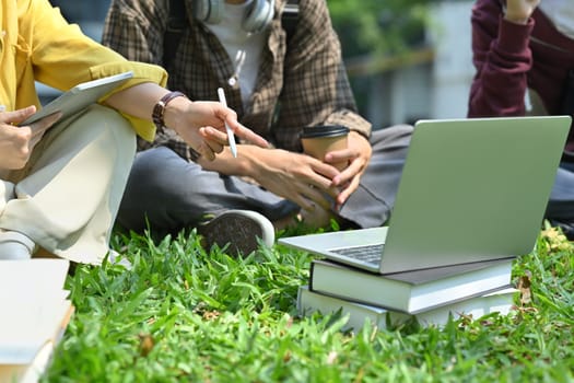 University students using laptop and working on group project at outdoor. Education, technology and community concept.