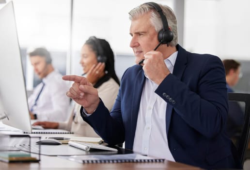Man, call center and pointing to computer in office while working on customer service in workplace. Telemarketing, focus and mature person, male sales agent or consultant talking or consulting online.