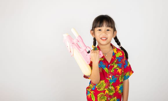 Happy Songkran Day, Asian kid girl with floral shirt hold water gun, Thai child funny hold toy water pistol and smile, isolated on white background, Thailand Songkran festival national culture concept