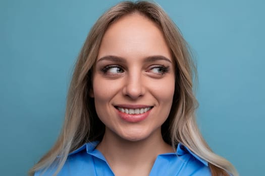beautiful young woman in a blue shirt smiling cheerfully on a blue background.