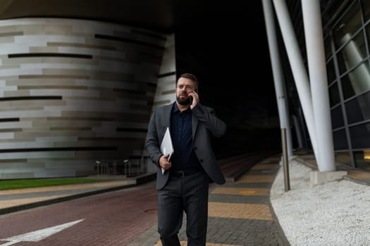 businessman rushing to meet him talking on the phone with a laptop in his hands.