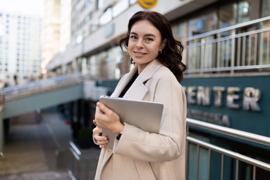 Business woman with a laptop in her hands on the background of the city.