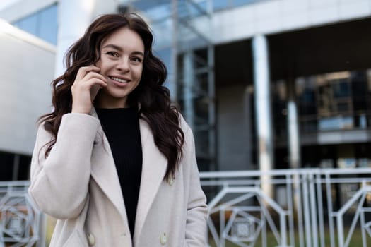 adult business woman talking on a mobile phone on the background of a modern building.